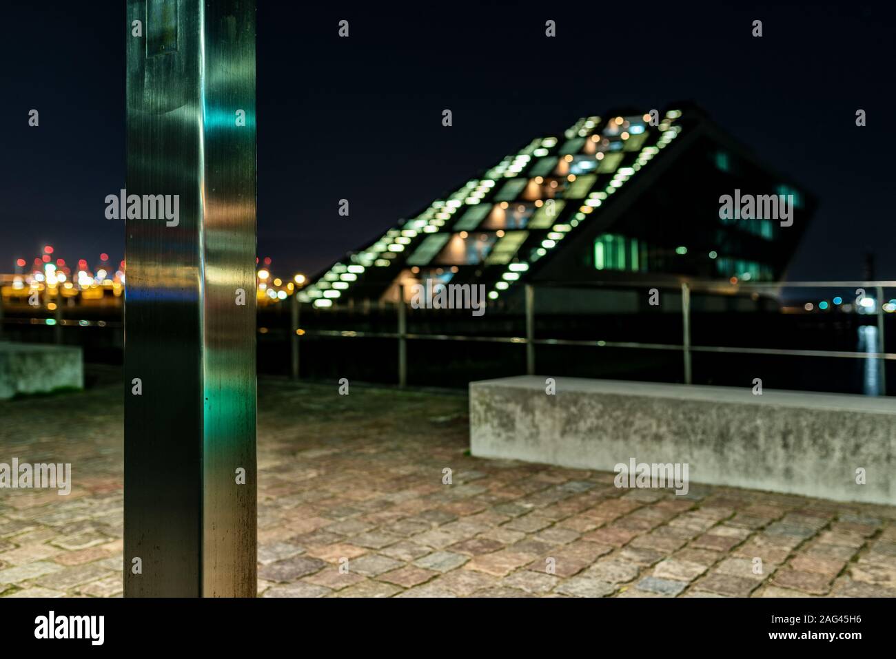 Primo piano di una colonna di metallo sul marciapiede di pietra in città di notte Foto Stock