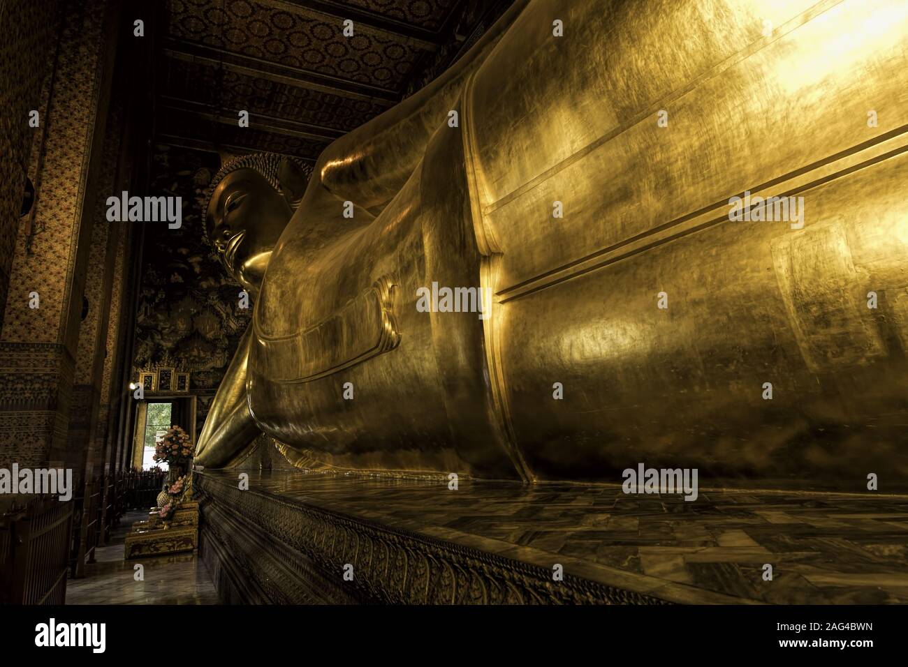 Statua dorata del Buddha reclinato all'interno di un tempio con splendidi motivi Foto Stock