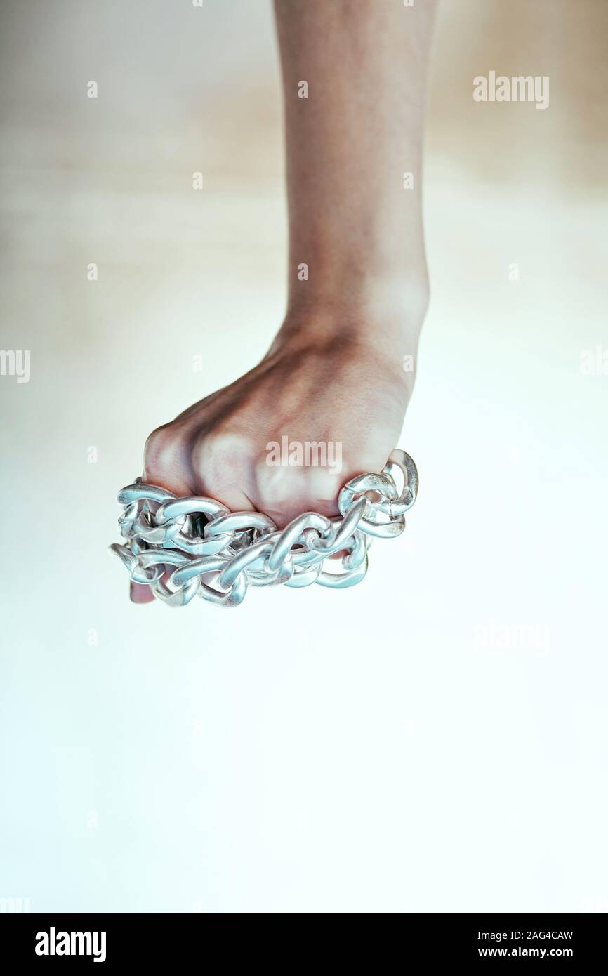 Colpo verticale di un braccio che tiene le catene d'argento su un sfondo bianco Foto Stock