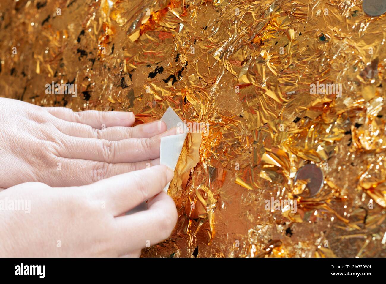 Mano di doratura buddista oro foglietto sulla palla dorata nel tempio per pregare e adorare il buddha Foto Stock