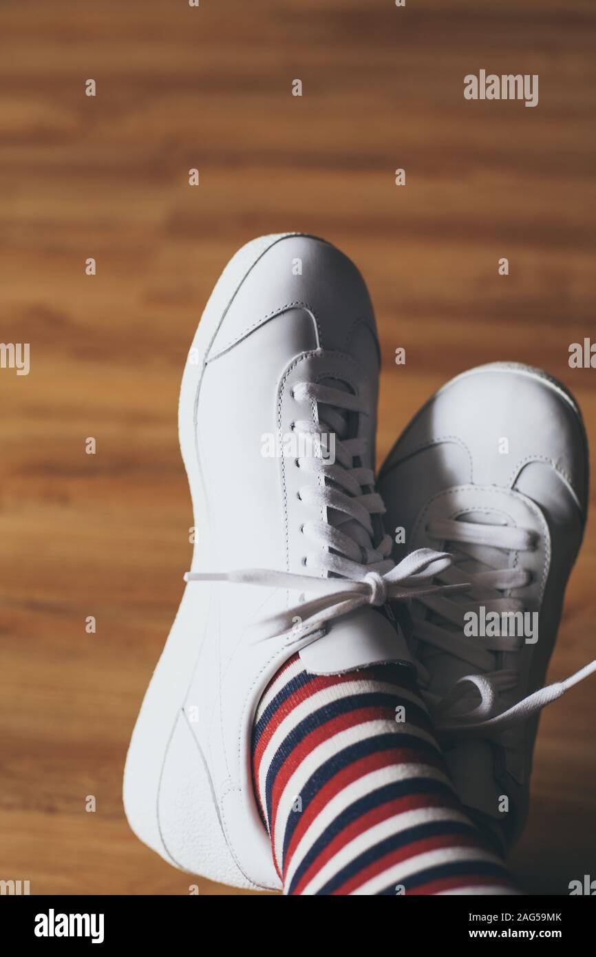 Immagine verticale dei piedi di una persona che indossa scarpe bianche e  calze a righe rosse, blu e bianche Foto stock - Alamy