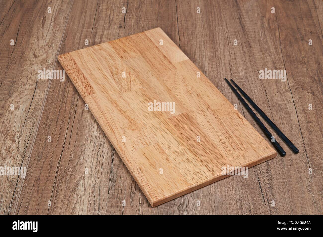 Elegante vassoio in legno sulla tabella strutturata con bacchette Foto Stock