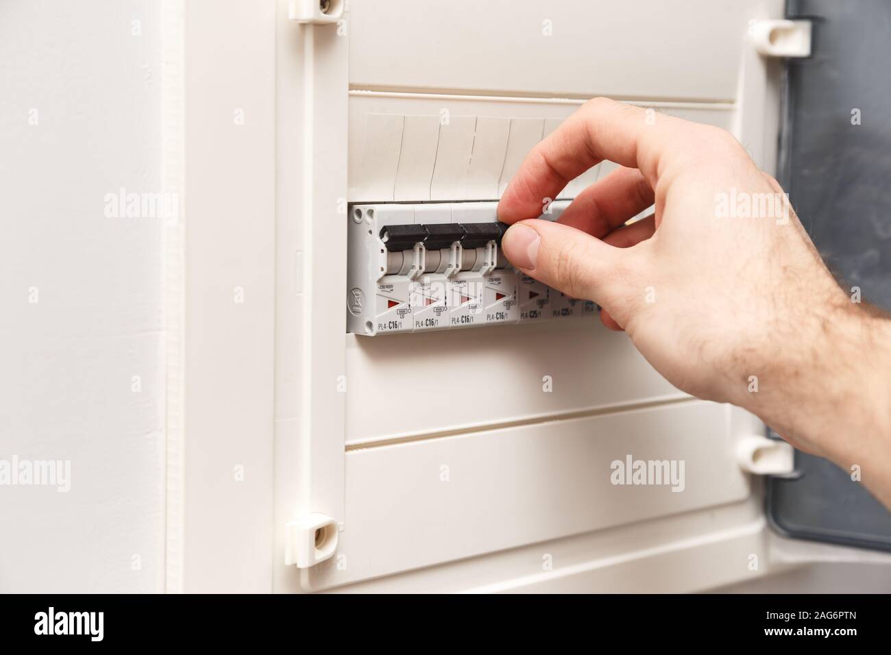 Un RCD interruttore di circuito stampato con molti interruttori. Mano d'uomo è di circa spegnere Foto Stock