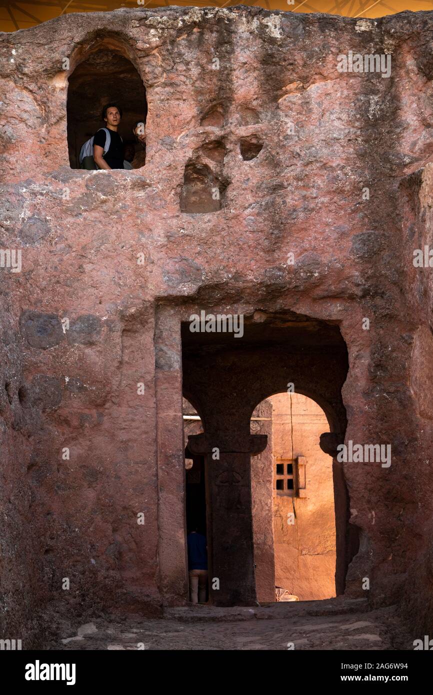 Etiopia, Amhara Region, Lalibela, i visitatori all'interno di scommessa cappella Danagel guardando fuori della finestra di pietra Foto Stock