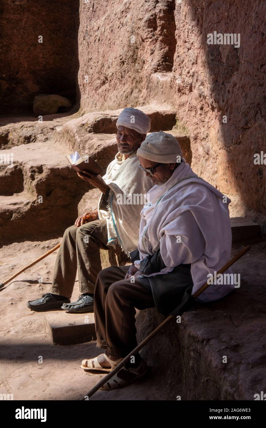 Etiopia, Amhara Region, Lalibela, Bet Maryam cortile della chiesa, due sacerdoti la lettura vangelo nella luce del sole Foto Stock