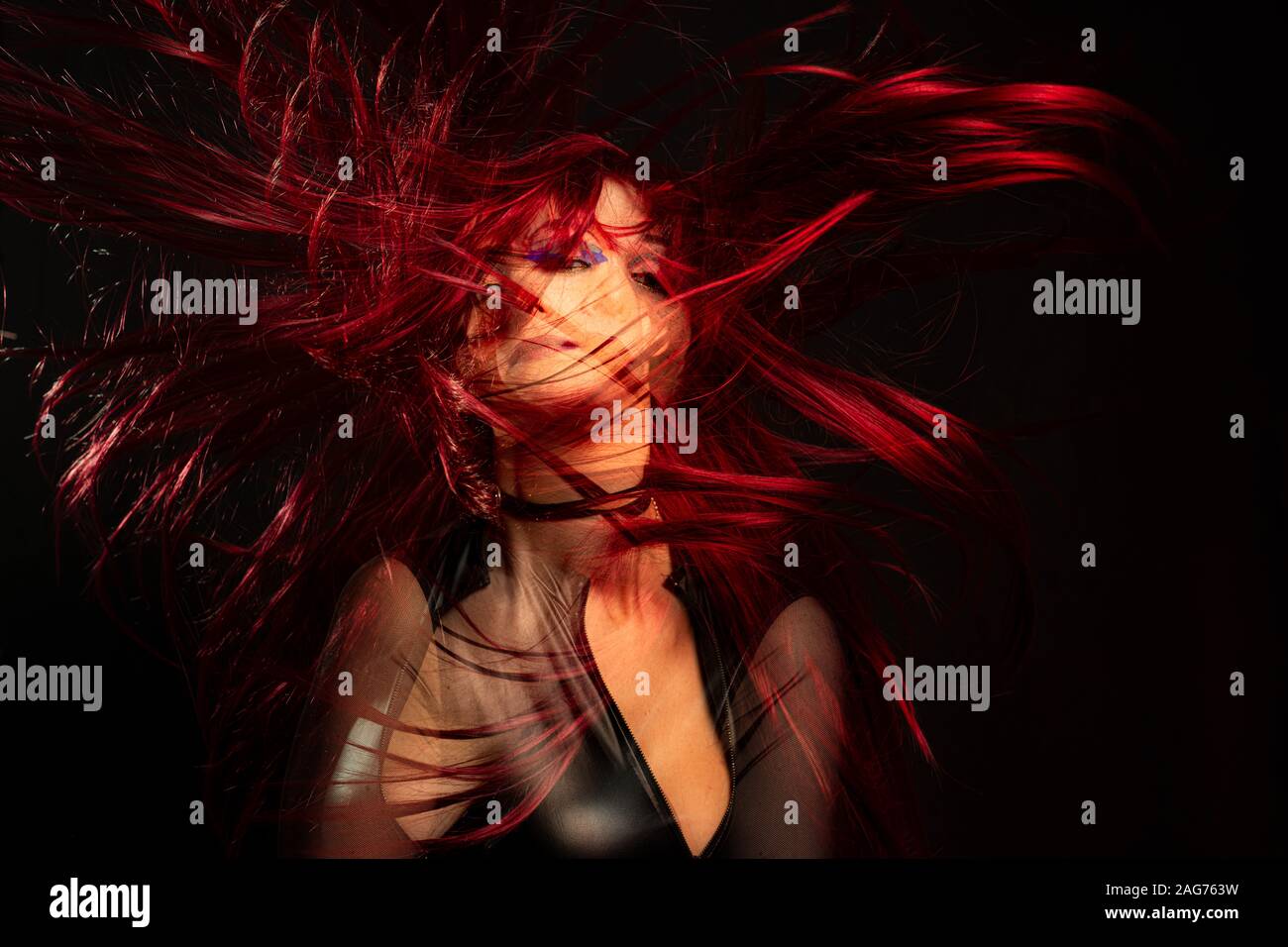 Una ragazza su uno sfondo nero con doppia esposizione con i capelli rossi al vento Foto Stock