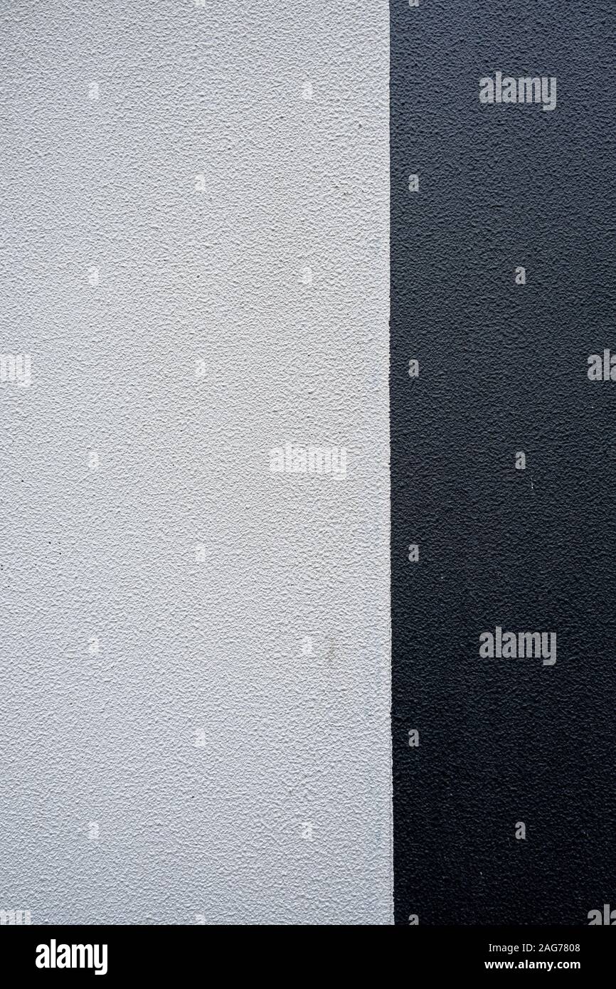 Textured parete in calcestruzzo diviso in due sezioni - bianco e nero. L'immagine verticale. Foto Stock