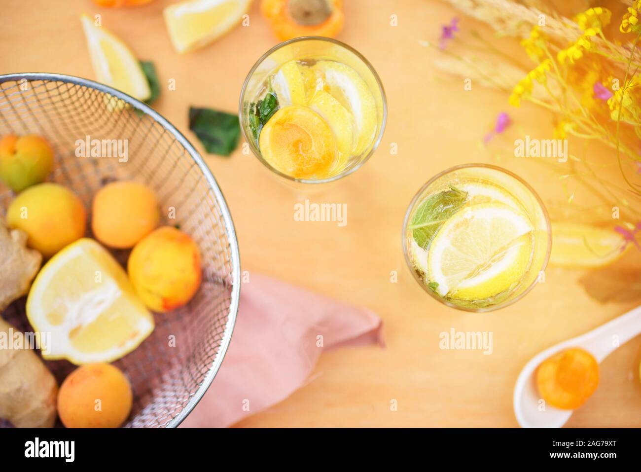 Estate limonata con limone, calce, zenzero menta, con fiori selvatici, albicocca sul tavolo. Bevande di raffreddamento Foto Stock
