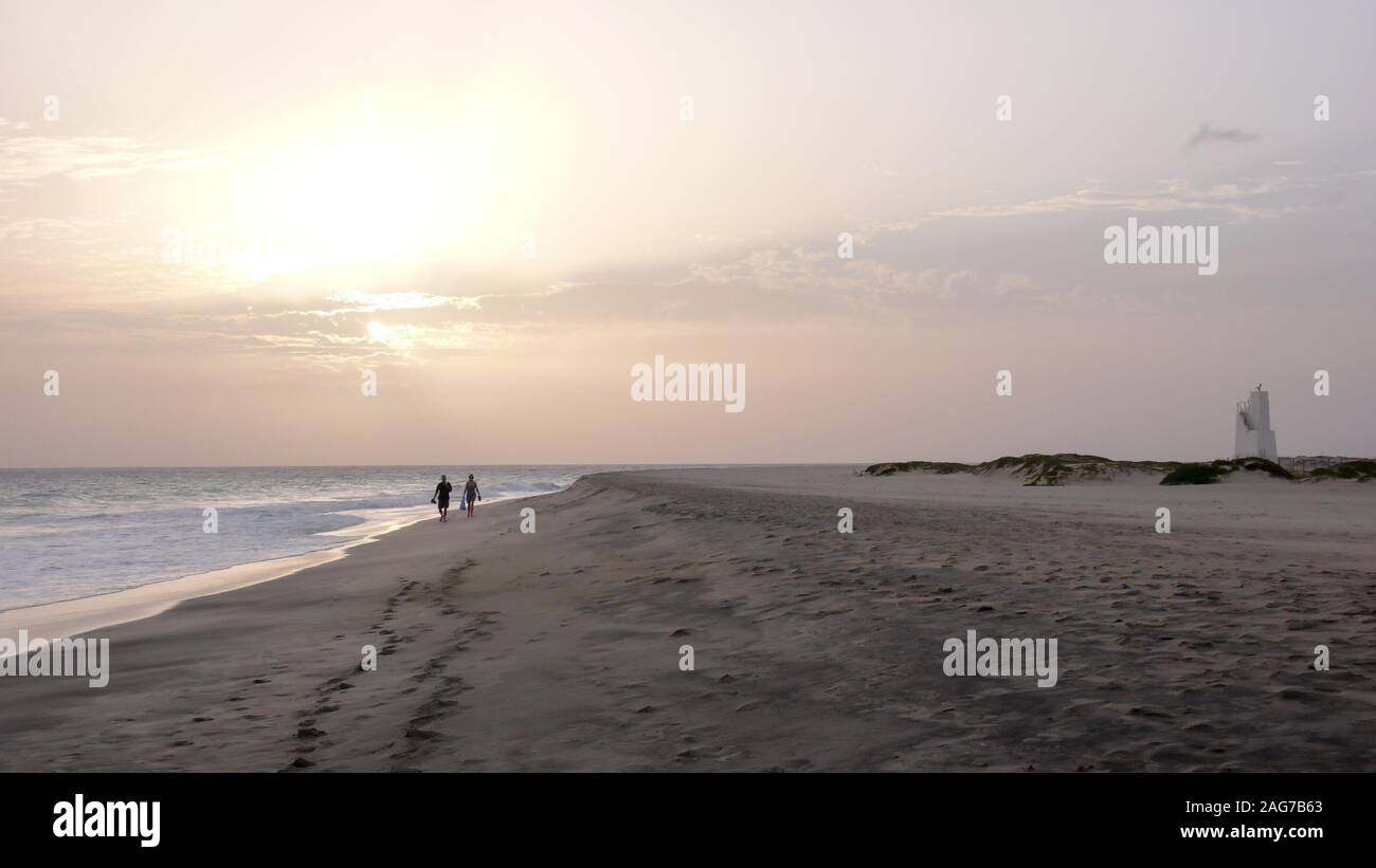 Un paio di godere di un tramonto a piedi su di una spiaggia appartata in Capo Verde Foto Stock