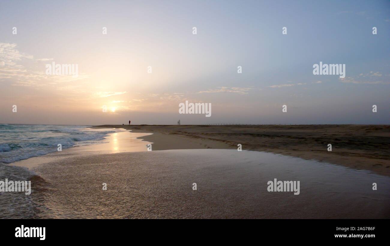 Una persona che gode di una passeggiata serale in una appartata spiaggia tropicale in Capo Verde al tramonto Foto Stock