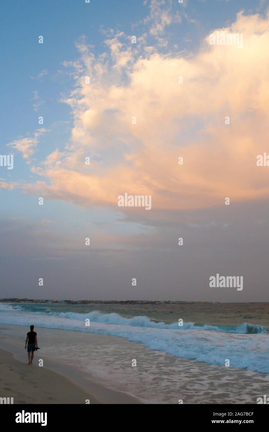 Una persona che gode di una passeggiata serale in una appartata spiaggia tropicale in Capo Verde al tramonto Foto Stock