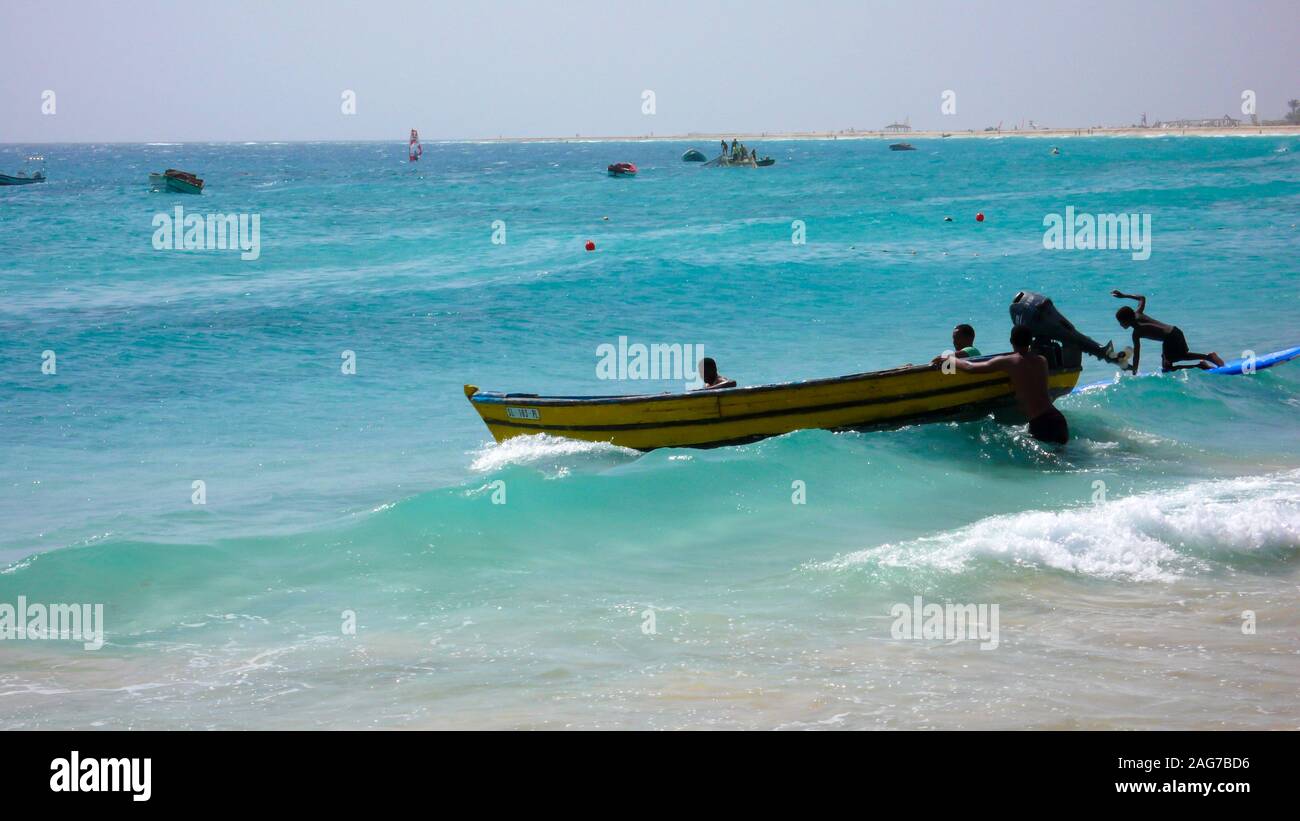 Santa Maria, Sal /Isole di Capo Verde - 19. Novembre, 2015: i pescatori africani il lancio di piccolo skiff di legno da una spiaggia tropicale sulle Isole di Capo Verde Foto Stock