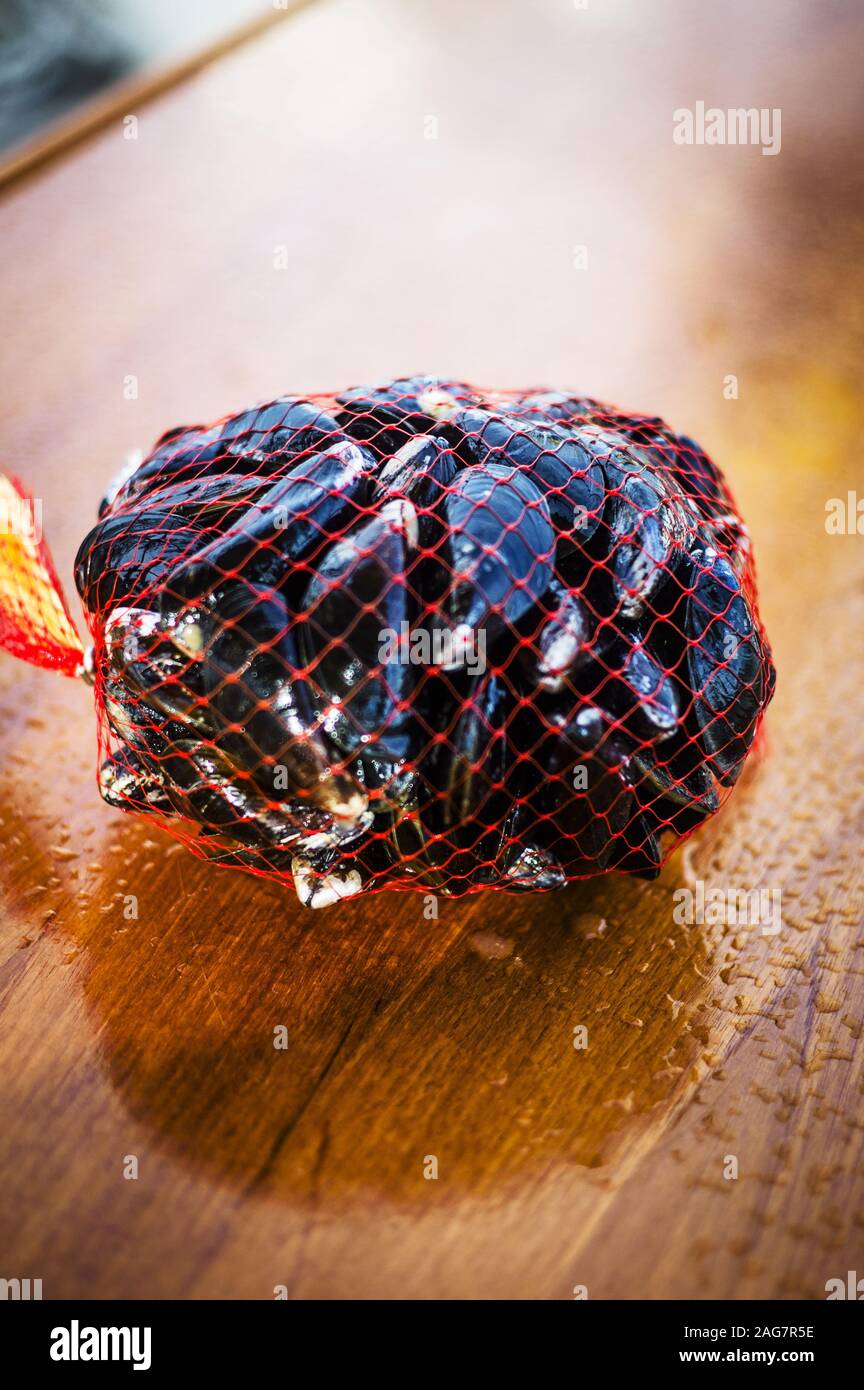 Colpo di closeup verticale di un sacchetto a rete riempito di cozze - perfetto per un articolo di ricetta Foto Stock