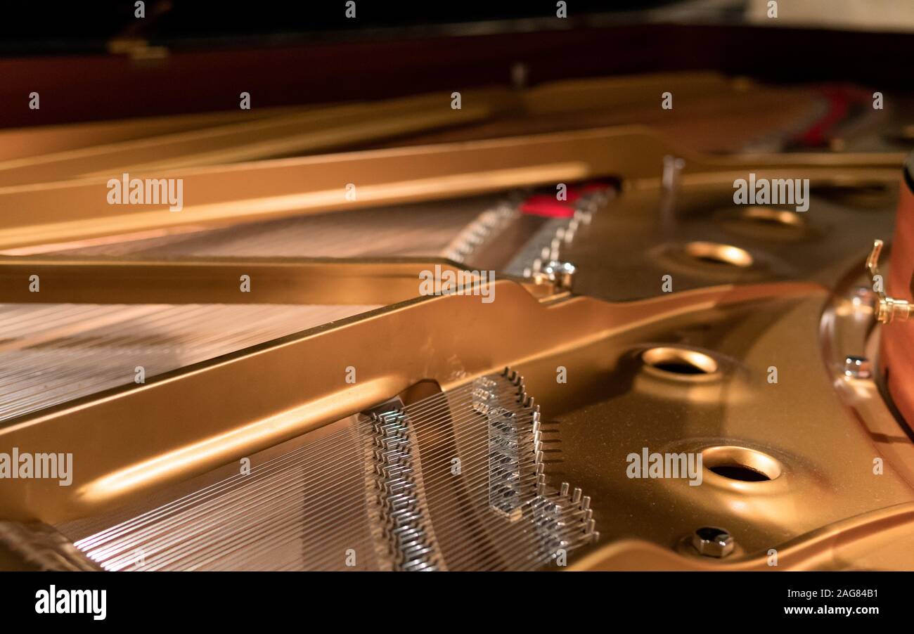 Primo piano della parte interna di un pianoforte dorato con corde d'argento Foto Stock