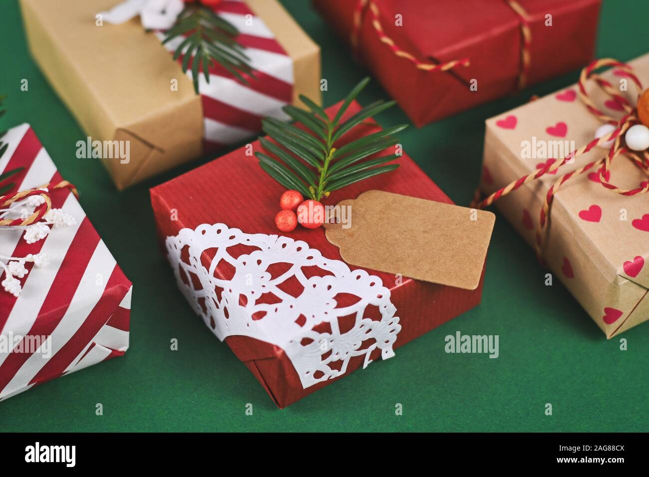 Bel rosso, bianco e marrone naturale decorato di Natale confezioni regalo con nastri e rami d abete su sfondo verde Foto Stock