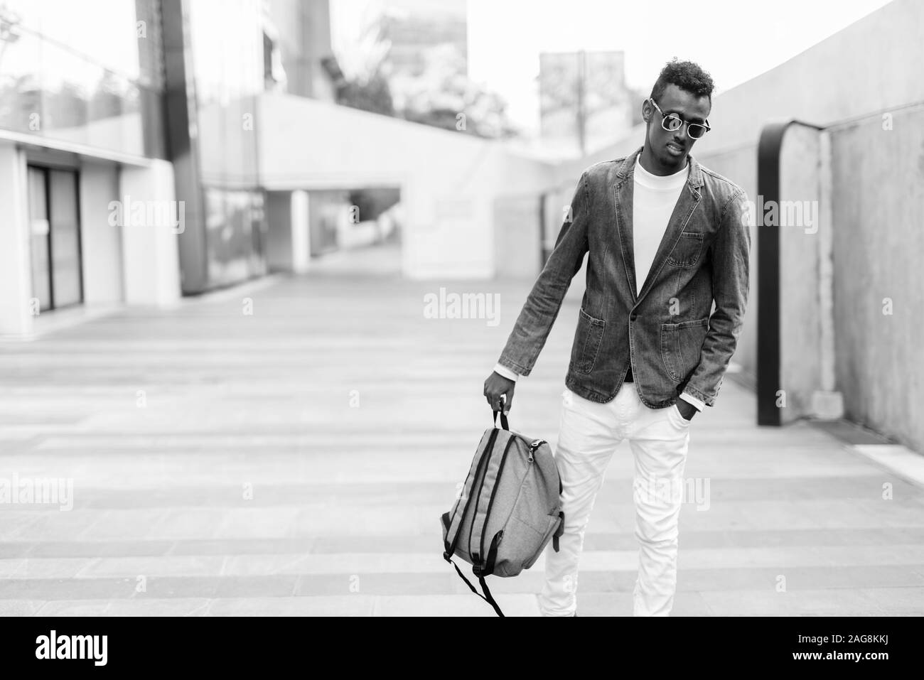 I giovani africani barbuto tourist uomo denim da indossare giacca e occhiali da sole nelle strade all'aperto Foto Stock