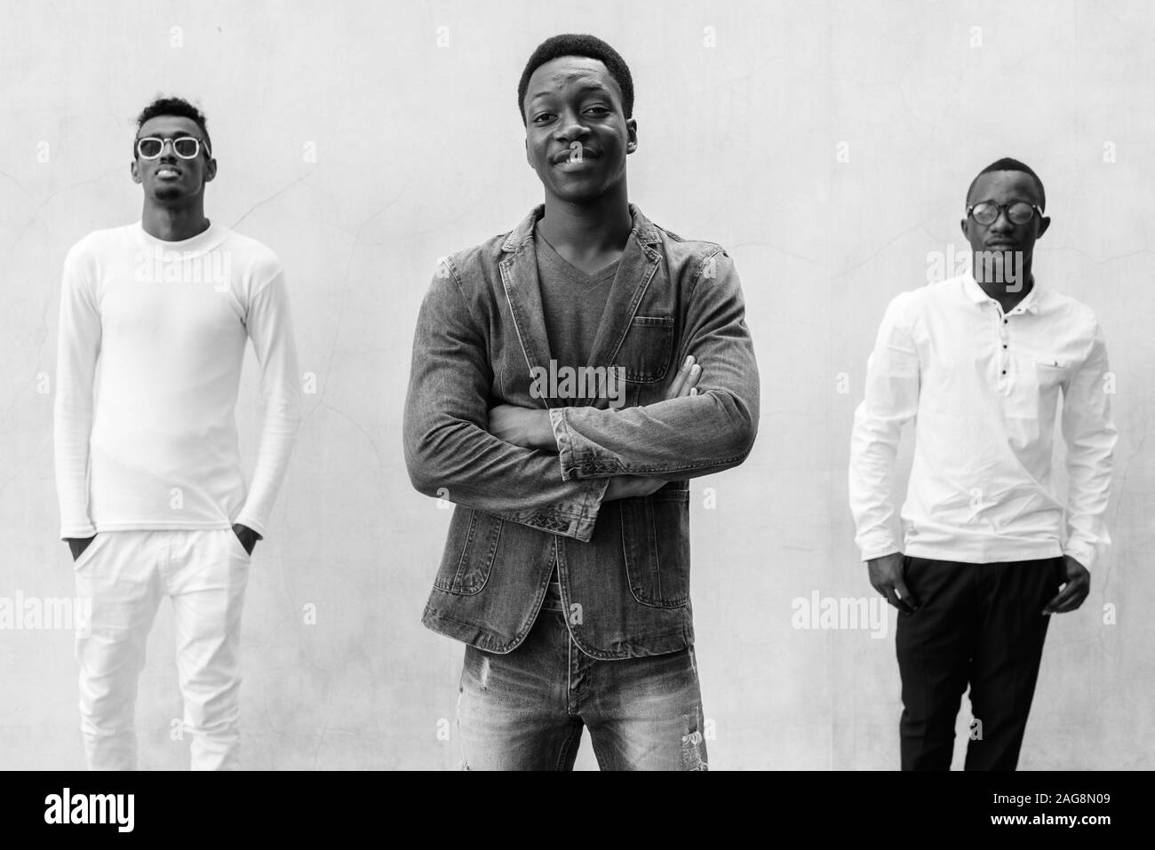Tre giovani uomini africani appendere fuori contro il muro di cemento all'aperto Foto Stock
