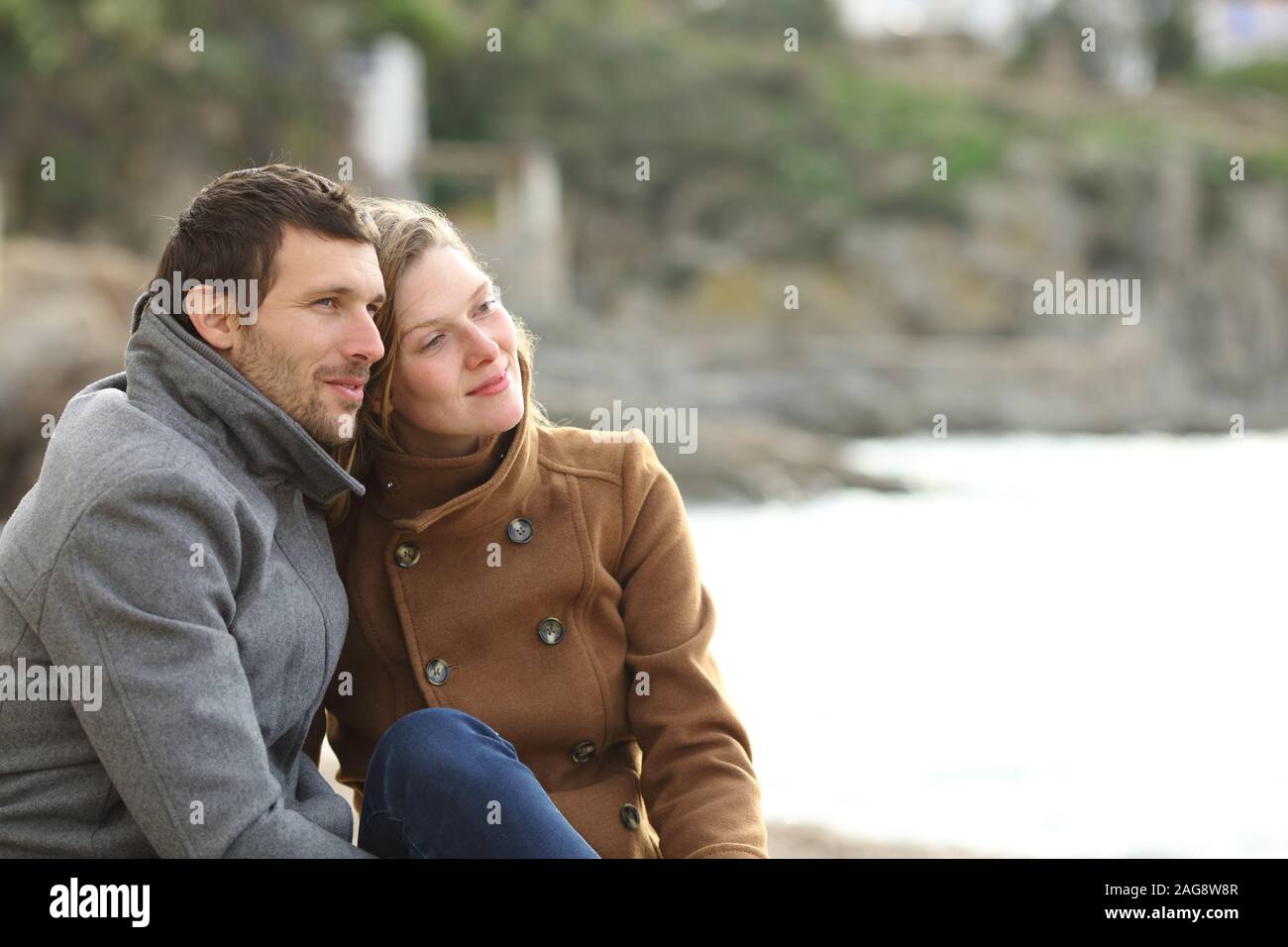 Rilassata paio di adulti contemplando views Seduto sulla spiaggia di vacanze invernali Foto Stock