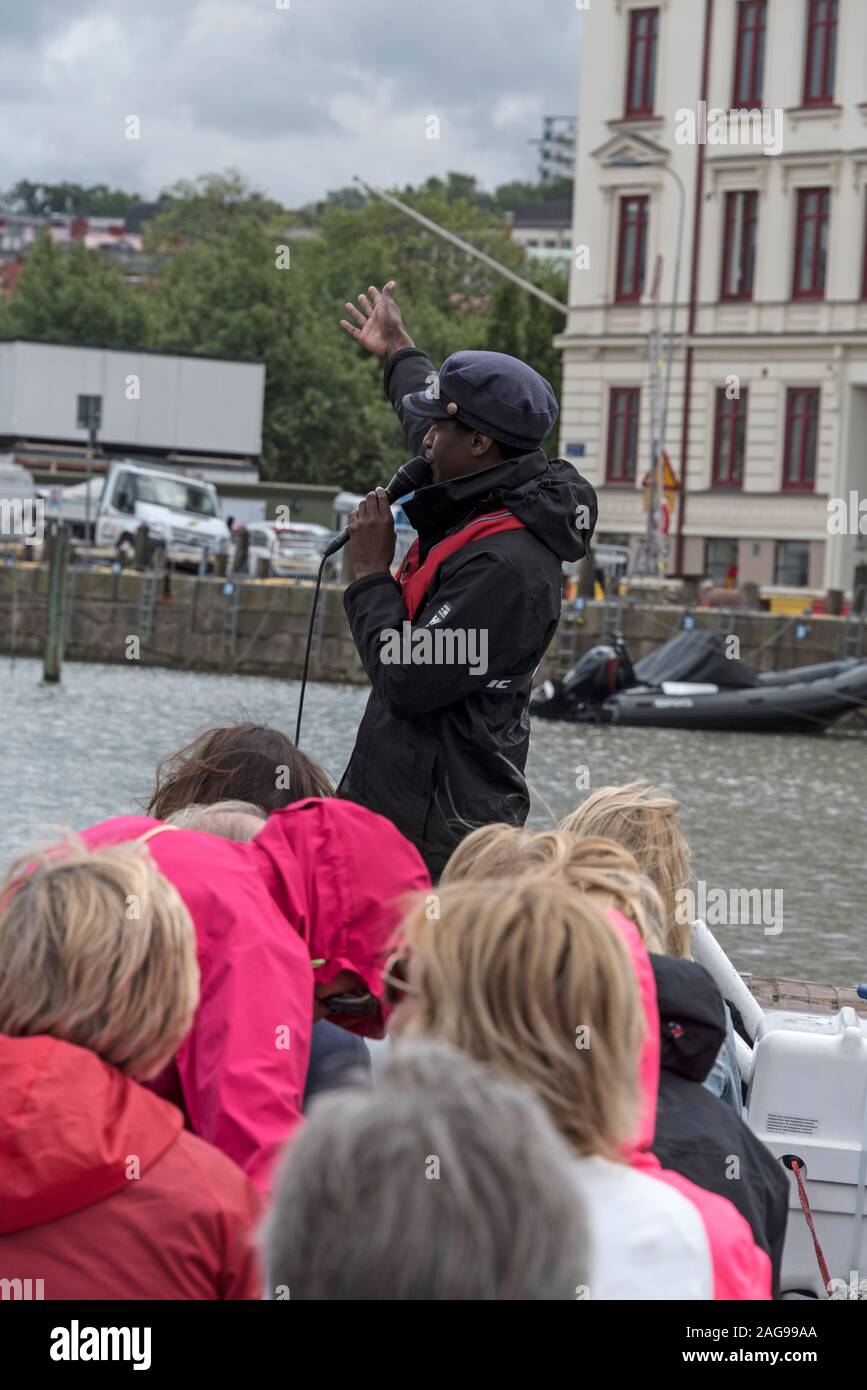 Una barca guida alla parte anteriore dell'imbarcazione turistica La Paddan gita turistica, portante un gruppo di turisti su uno dei canali a Gothenburg, Svezia. Foto Stock