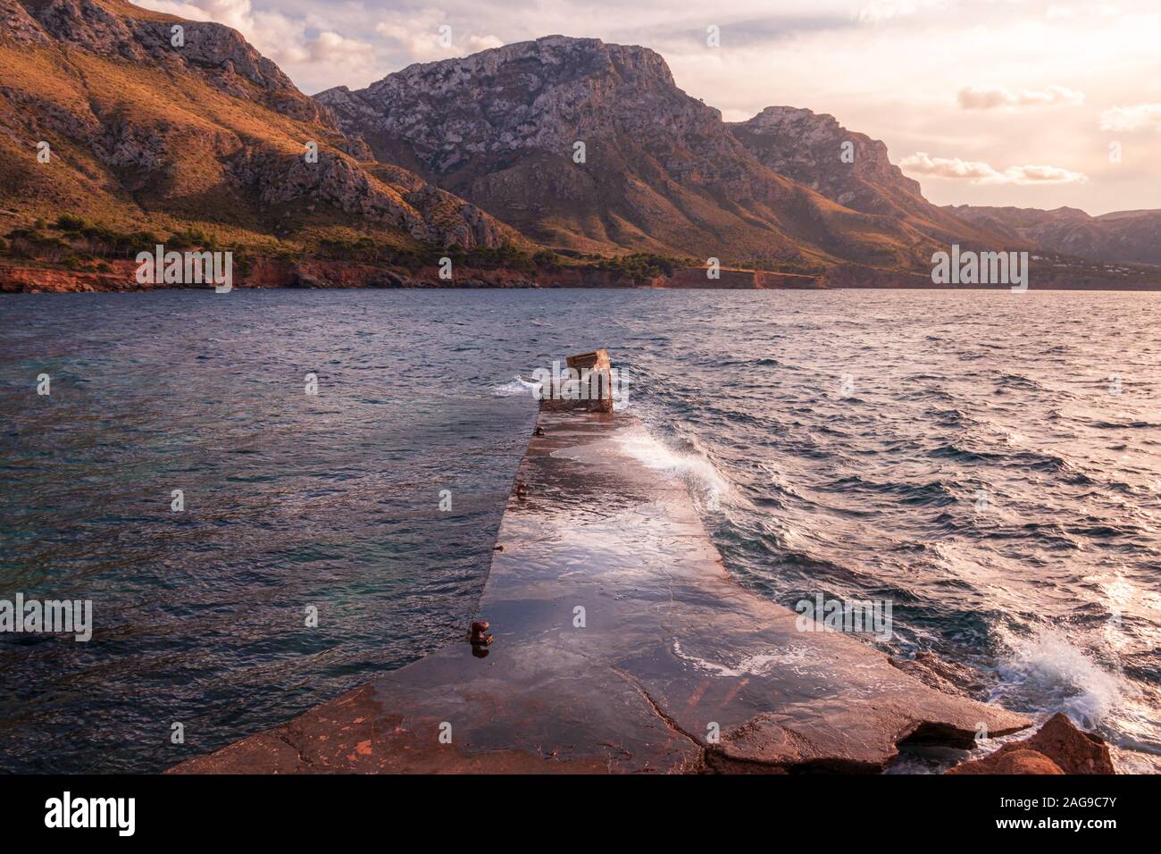 Stone jetty/pier El calo nei pressi di Betlem e Colonia de Sant Pere, verdi colline con bella luce, pomeriggio con cielo blu e nuvole bianche, Mallorca, S Foto Stock