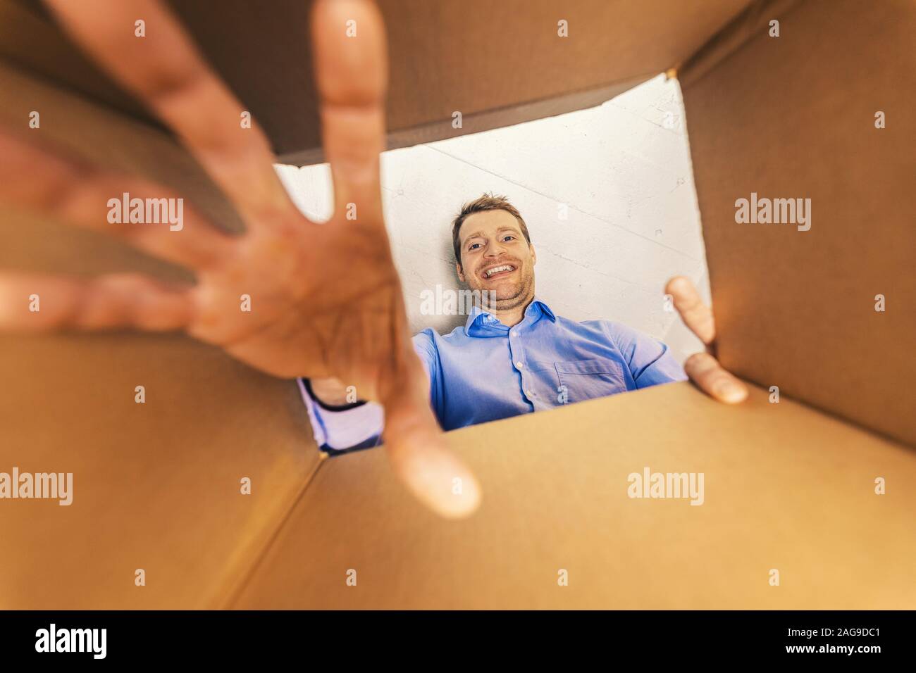 Uomo sorridente guardando all'interno della scatola e il raggiungimento di beni Foto Stock