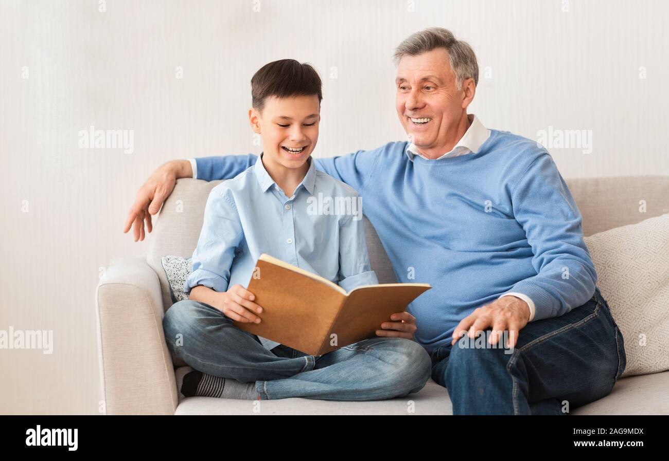 Ragazzo lettura Libro preferito con il nonno seduti a casa Foto Stock
