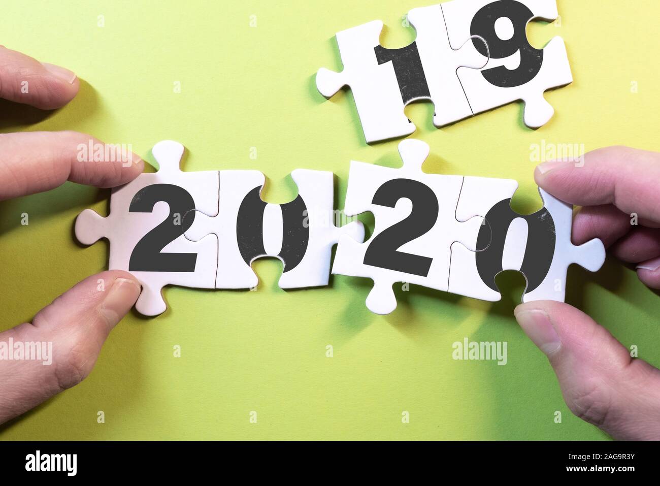 Anno nuovo concetto con vista dall'alto di mani sostituendo i pezzi del puzzle con 2019 a 2020 Foto Stock