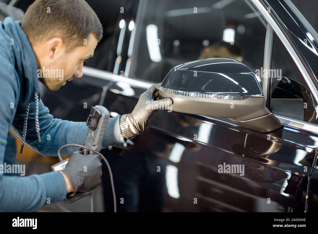 Auto di servizio lavoratore esaminando il corpo del veicolo per i graffi e i danni, prendendo un auto per auto professionali dettagliati. Professional body auto il concetto di ispezione Foto Stock