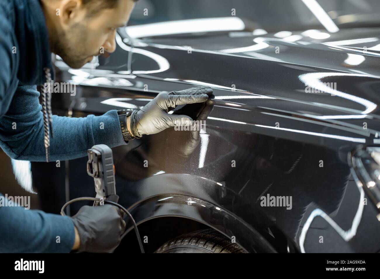 Auto di servizio lavoratore esaminando il corpo del veicolo per i graffi e i danni, prendendo un auto per auto professionali dettagliati. Professional body auto il concetto di ispezione Foto Stock