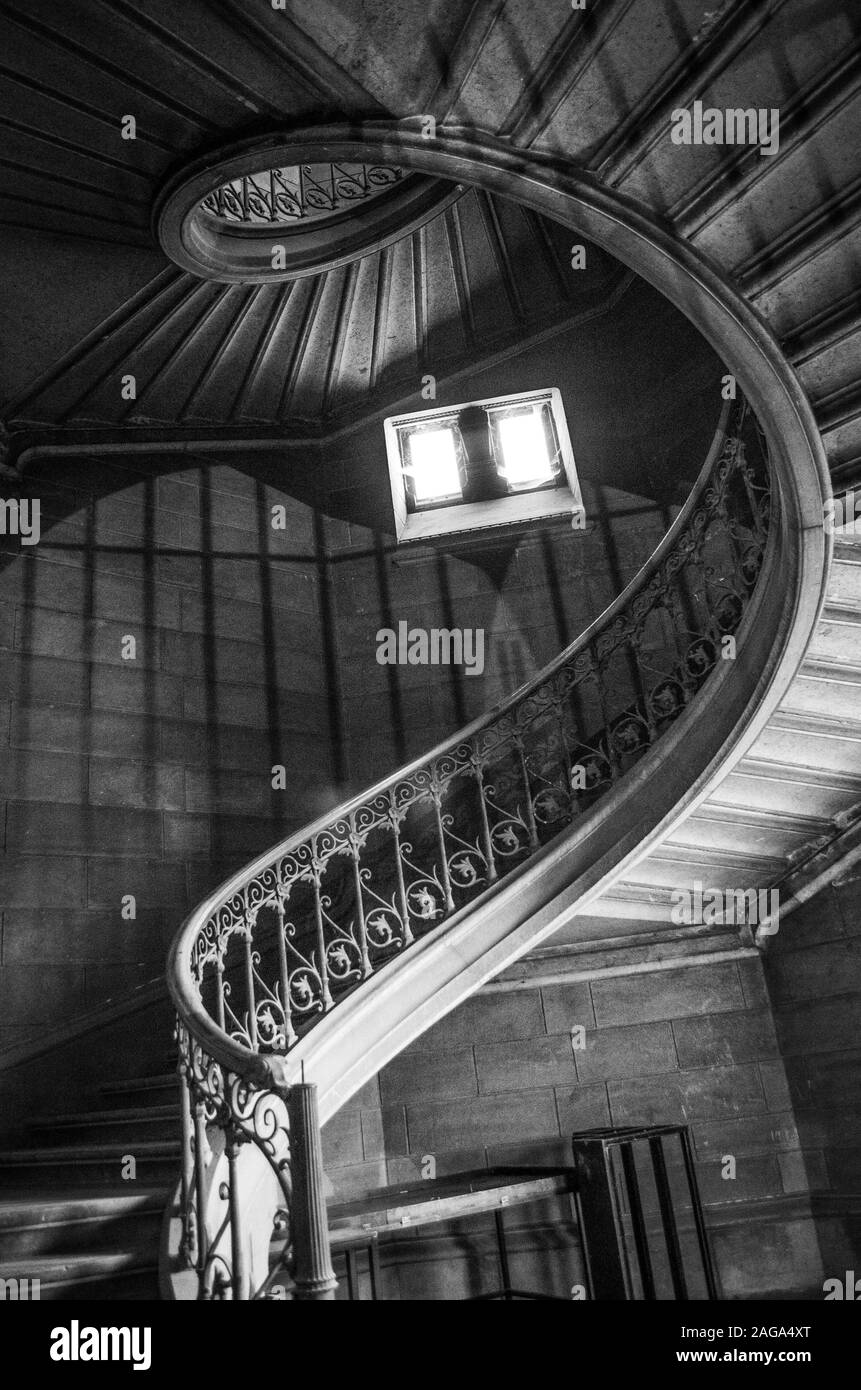 Immagine verticale in scala di grigi ad angolo basso di una scala in un antico edificio Foto Stock