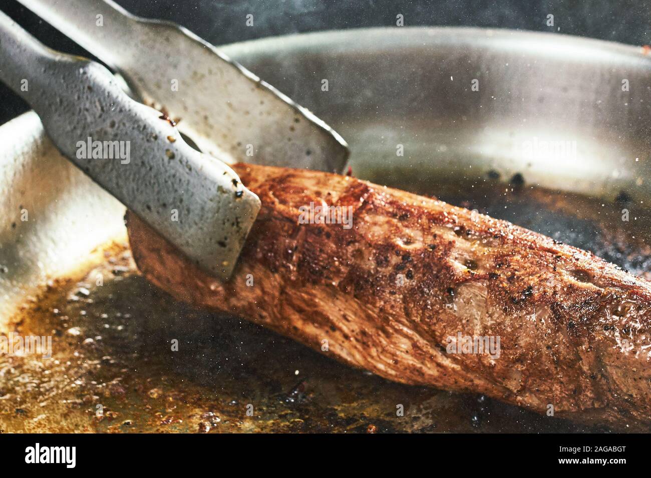 La cottura di carni bovine in un ristorante. bistecca e chef. closeup pezzo di carne arrosto Foto Stock