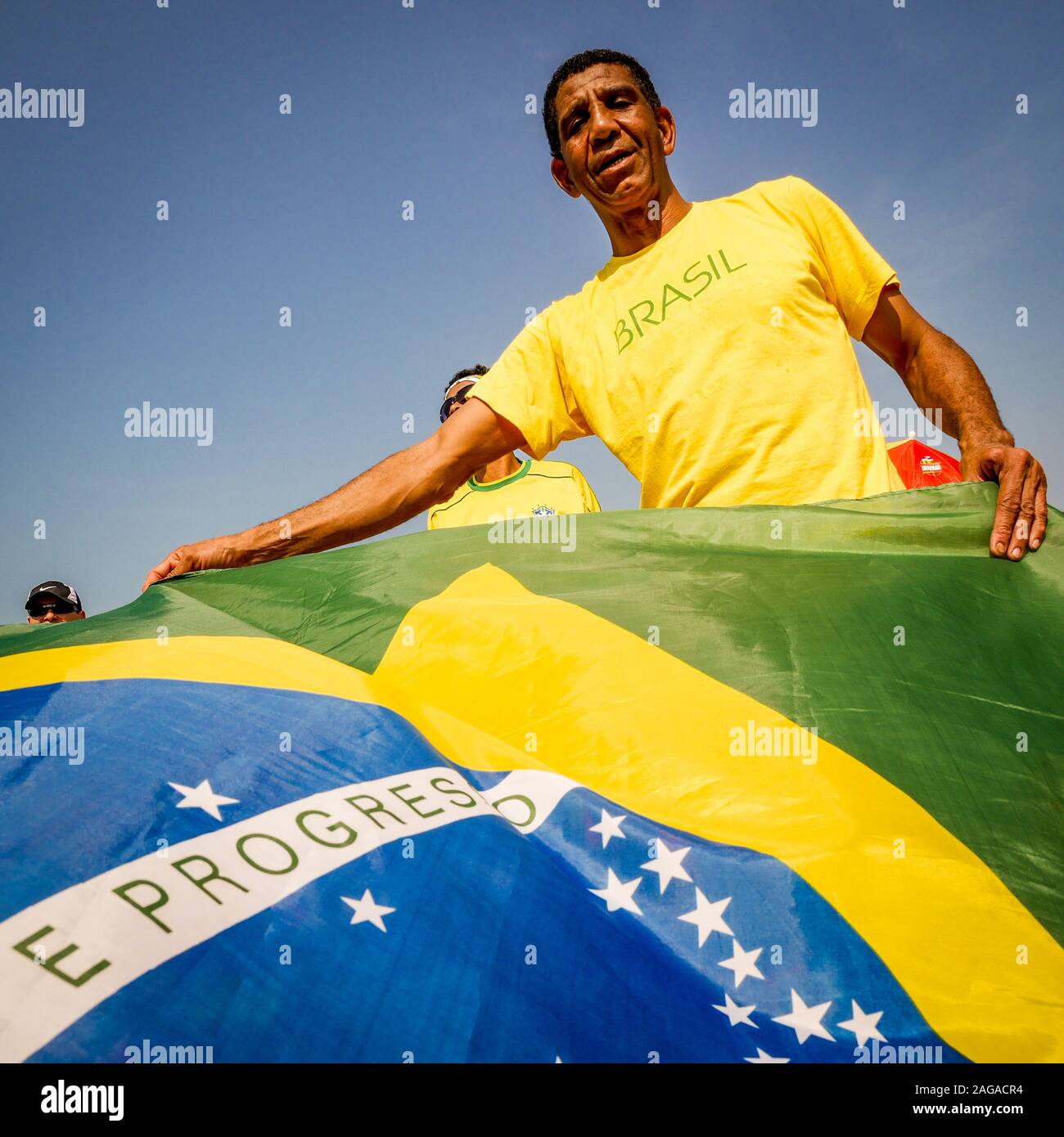 Orgoglioso uomo brasiliano. Un orgoglioso e patriottico uomo brasiliano indossando i suoi colori nazionali e agitando il suo paese a bandiera. Foto Stock