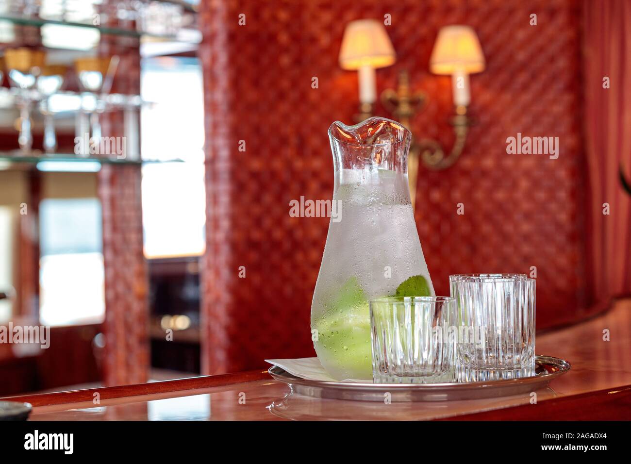 Colpo di closeup di un decanter con limonata di menta fredda e. occhiali su sfondo sfocato Foto Stock