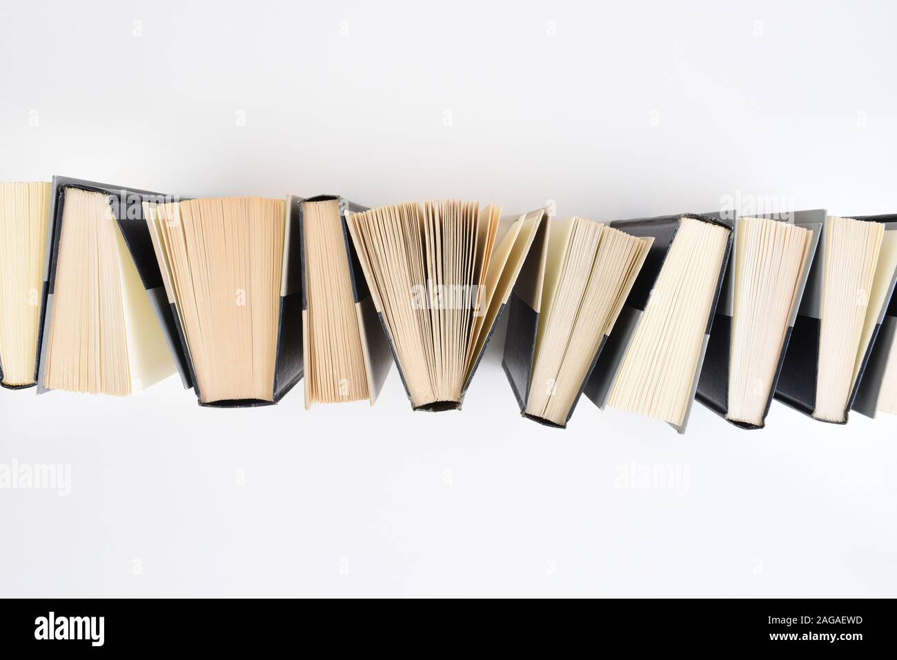 Angolo di alta immagine di una fila di libri in piedi sull'estremità su uno sfondo bianco. Foto Stock