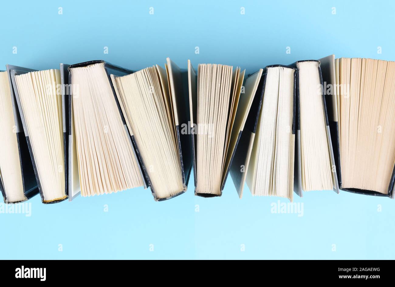 Angolo di alta immagine di una fila di libri in piedi sull'estremità su un fondo azzurro. Foto Stock