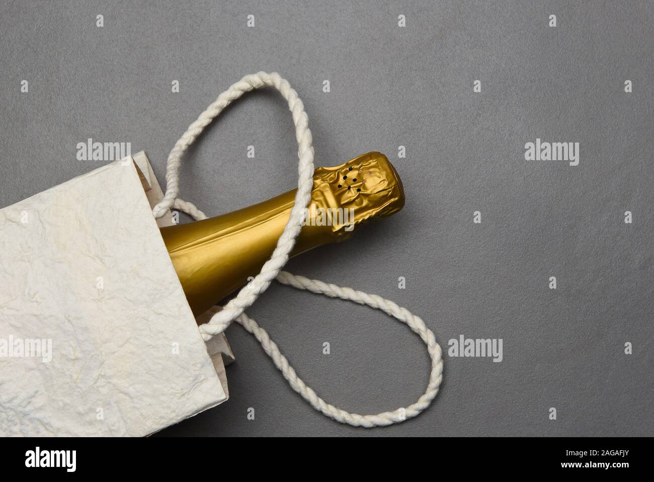 Champagne: borsa regalo con una bottiglia di vino spumante su grigio la superficie della piastrella. Foto Stock