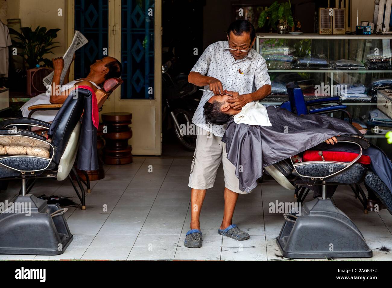 Un uomo avente una rasatura bagnata in un barbiere, Phnom Penh Cambogia. Foto Stock