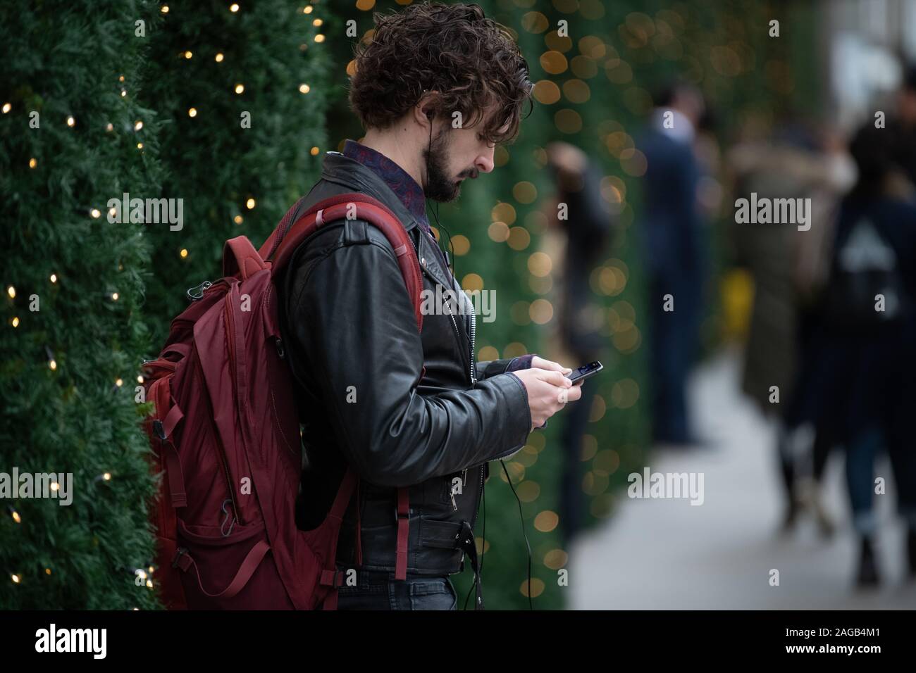 Uomo tra gli alberi di Natale al di fuori del Selfridges guardando al suo telefono cellulare Foto Stock