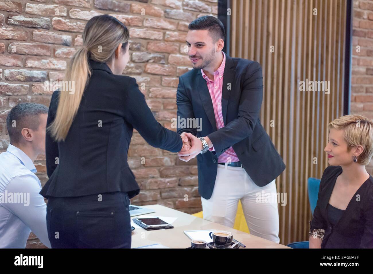 Lungo tempo non vedere. Allegro piacevole colleghi stringono le mani gli uni con gli altri e scambiare sorrisi prima di iniziare la riunione di affari Foto Stock