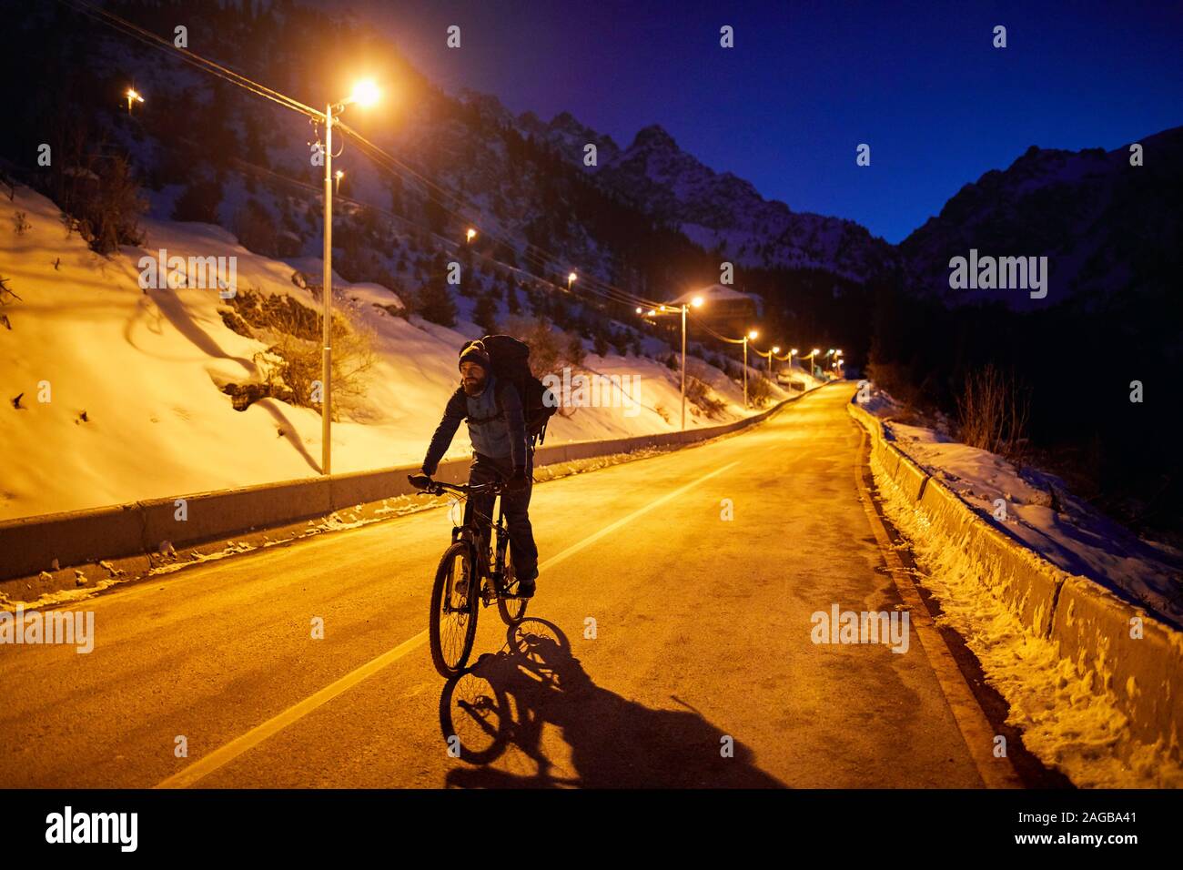 Ciclista in corse in strada di montagna a notte invernale Foto Stock