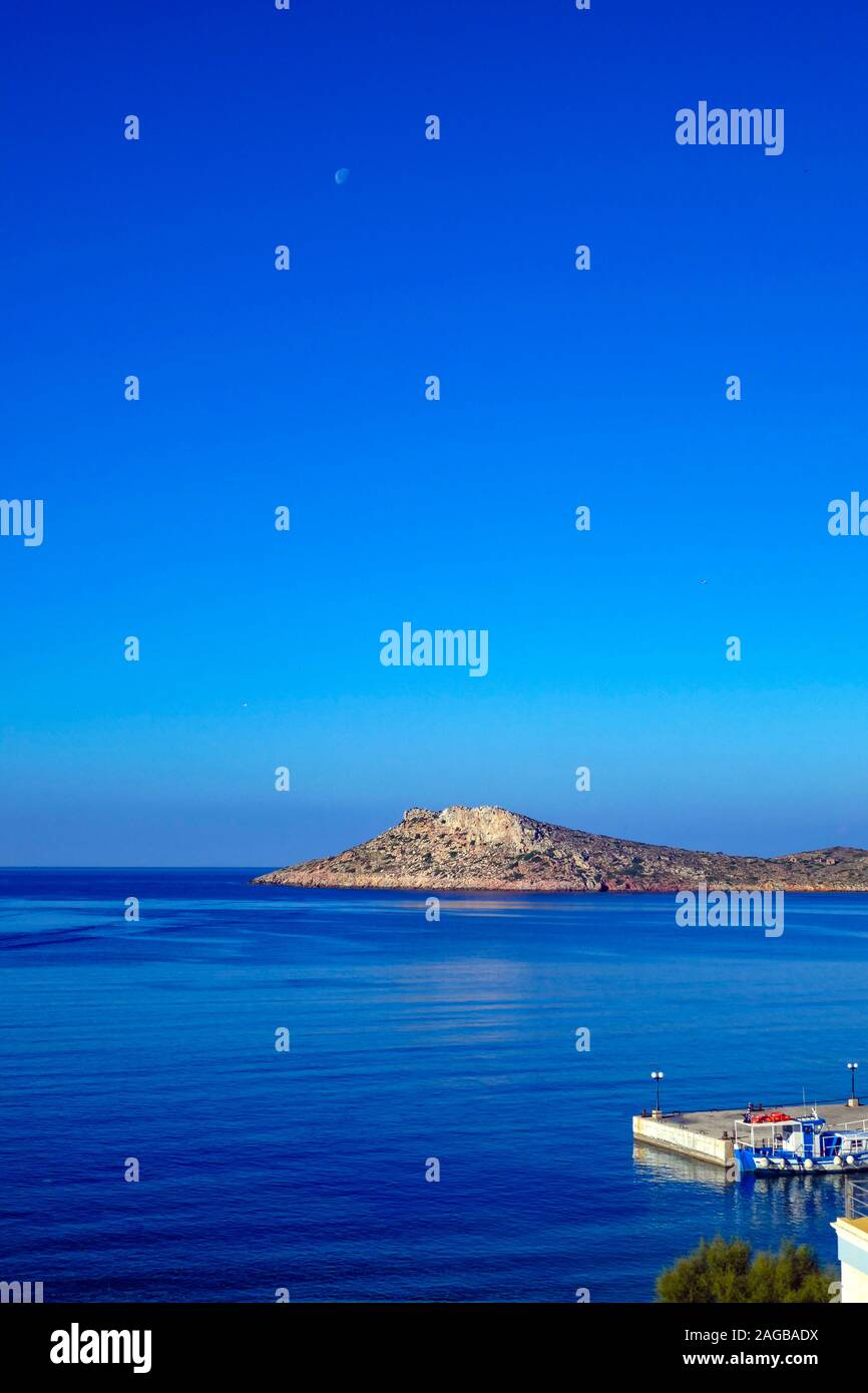 Luna calante con blu e bianco barca-taxi sulla calma mattina blu a Myrties Jetty, Kalymnos Grecia Foto Stock