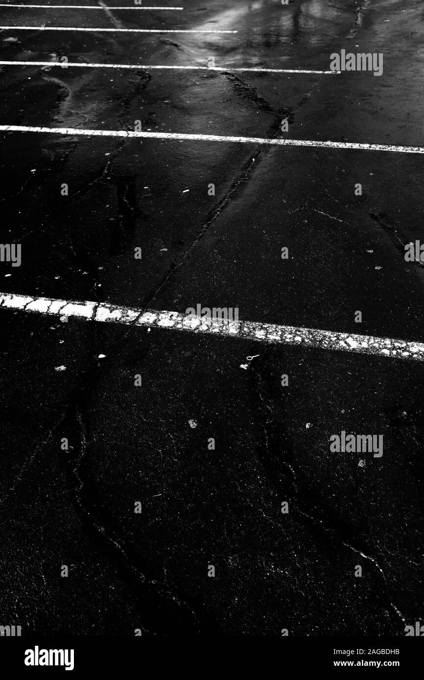 Immagine verticale in scala di grigi di un asfalto bagnato con linee bianche Foto Stock