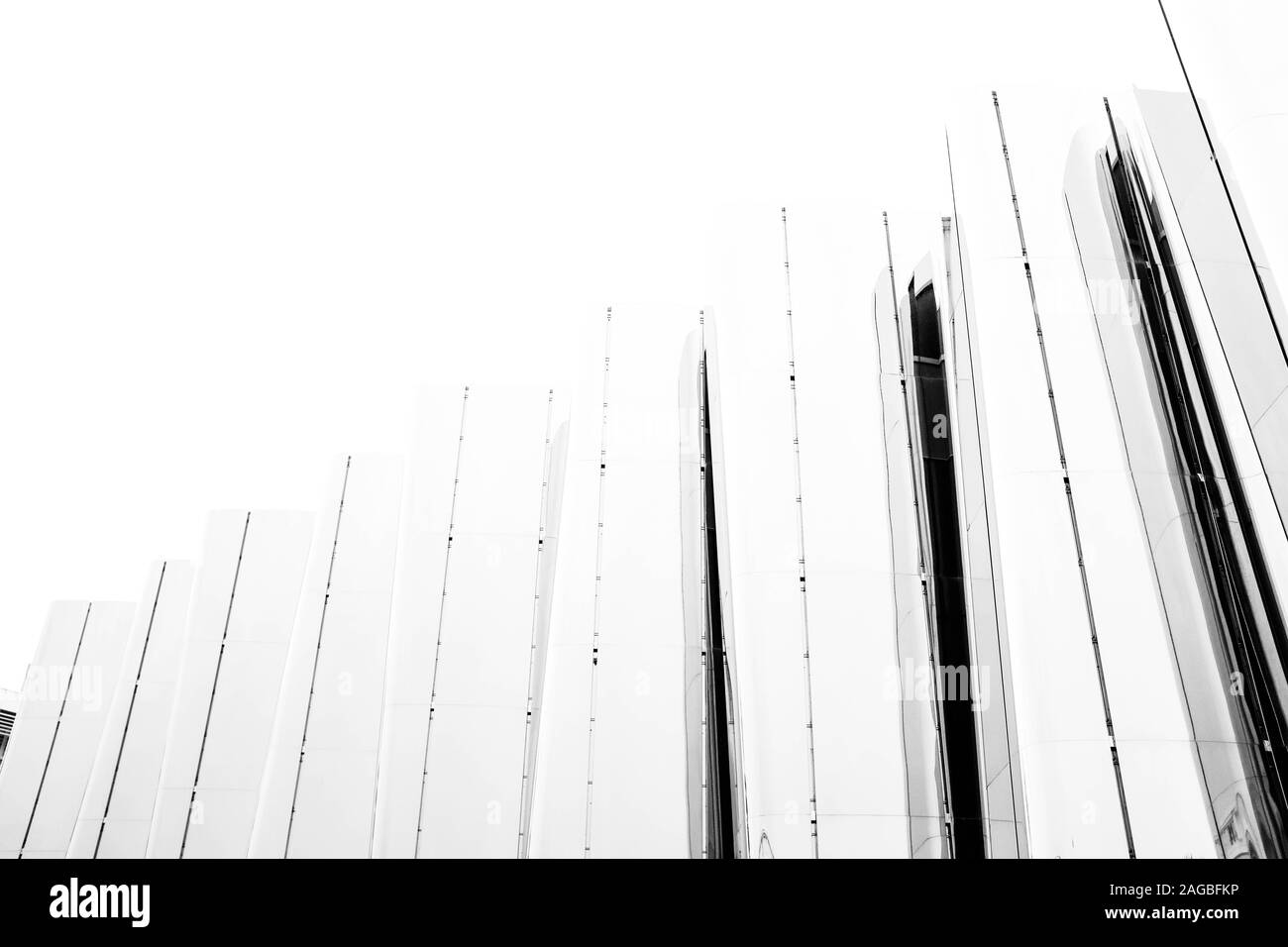 Immagine in scala di grigi ad angolo basso di una recinzione con pannelli di vetro sotto il cielo bianco Foto Stock