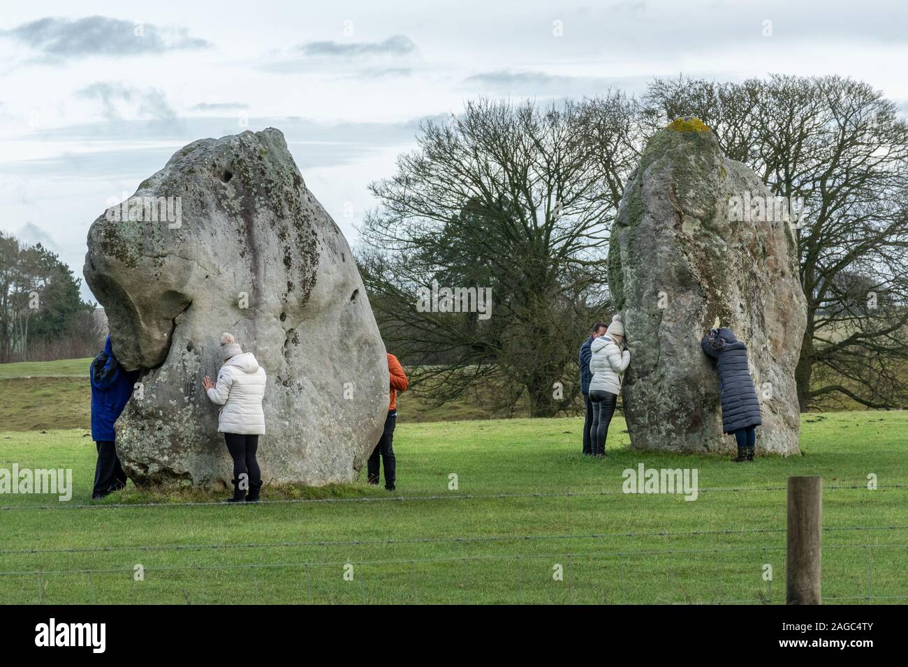 I visitatori ad Avebury Stone Circle toccando e abbracciando il neolitihic pietre per l'energia magnetica e di poteri di guarigione, Wiltshire, Inghilterra, Regno Unito Foto Stock