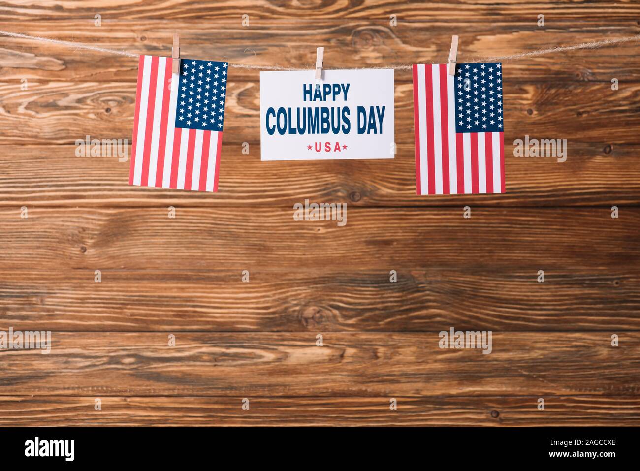 Scheda con happy Columbus day iscrizione tra bandiere nazionali d'America su una superficie di legno Foto Stock