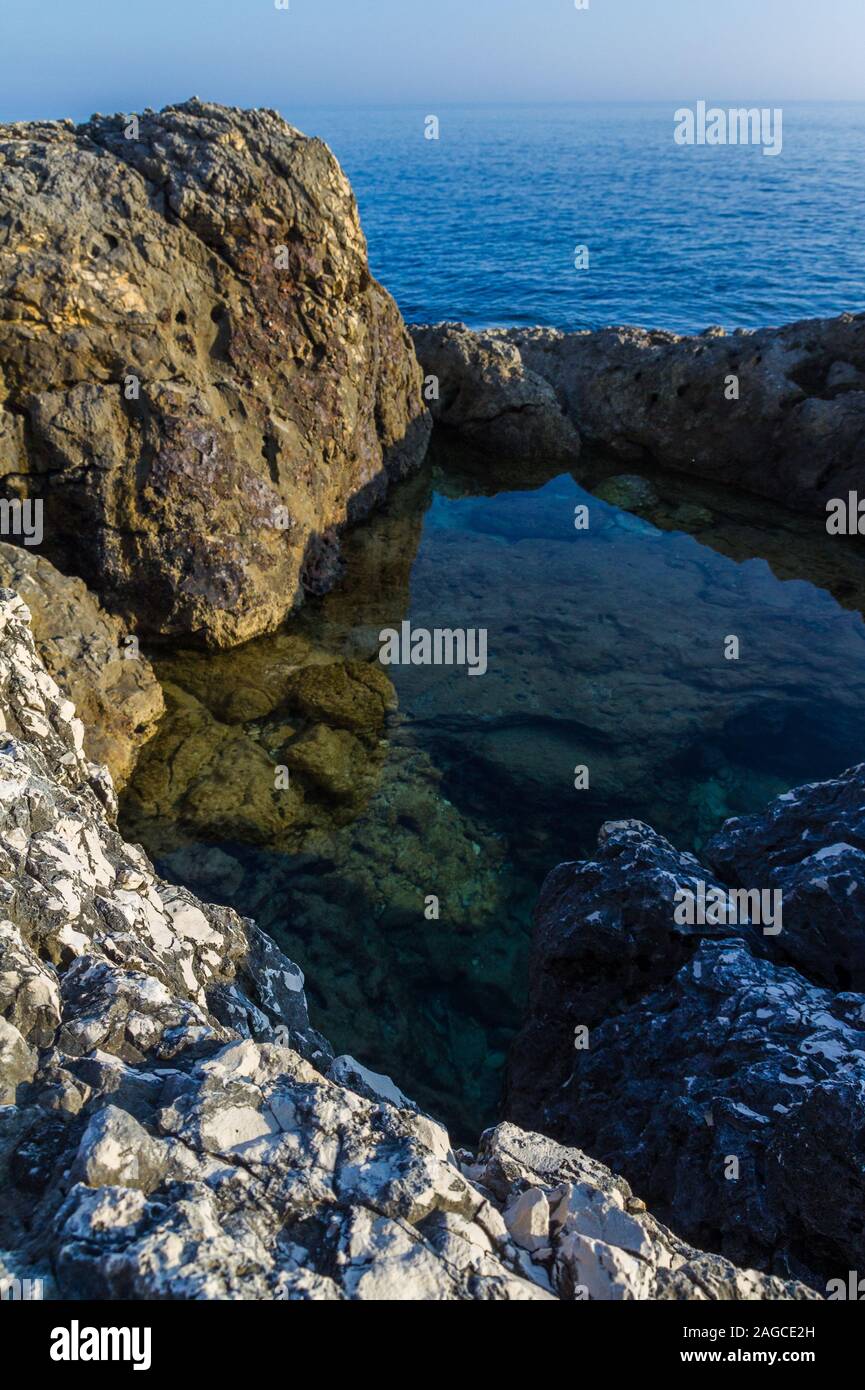 Immagine verticale di un piccolo lago formato all'interno delle rocce della costa di Kamenjak in Istria, Croazia Foto Stock