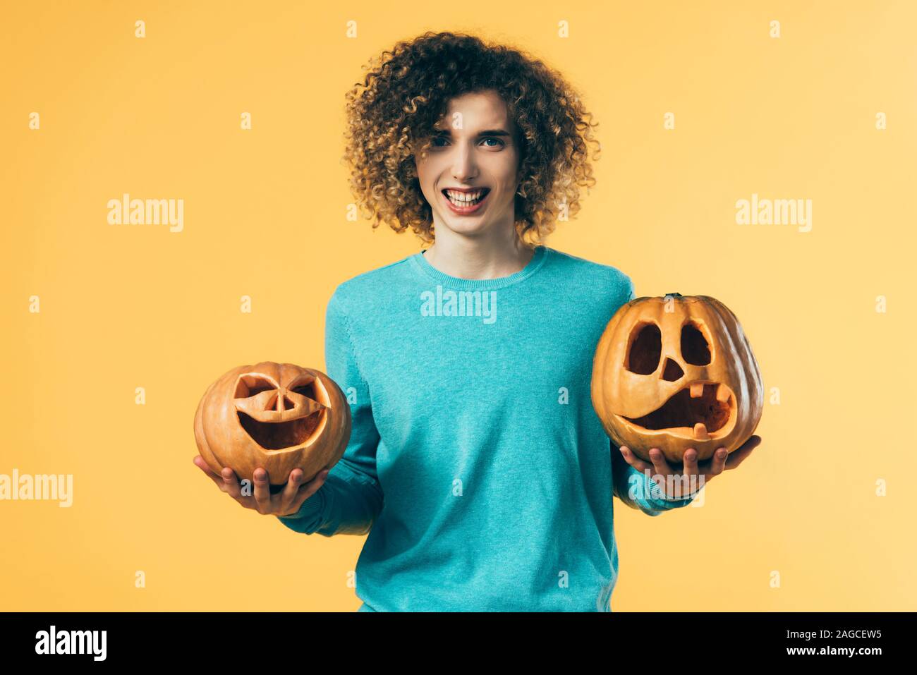 Curly adolescente holding zucche di Halloween isolato su giallo Foto Stock