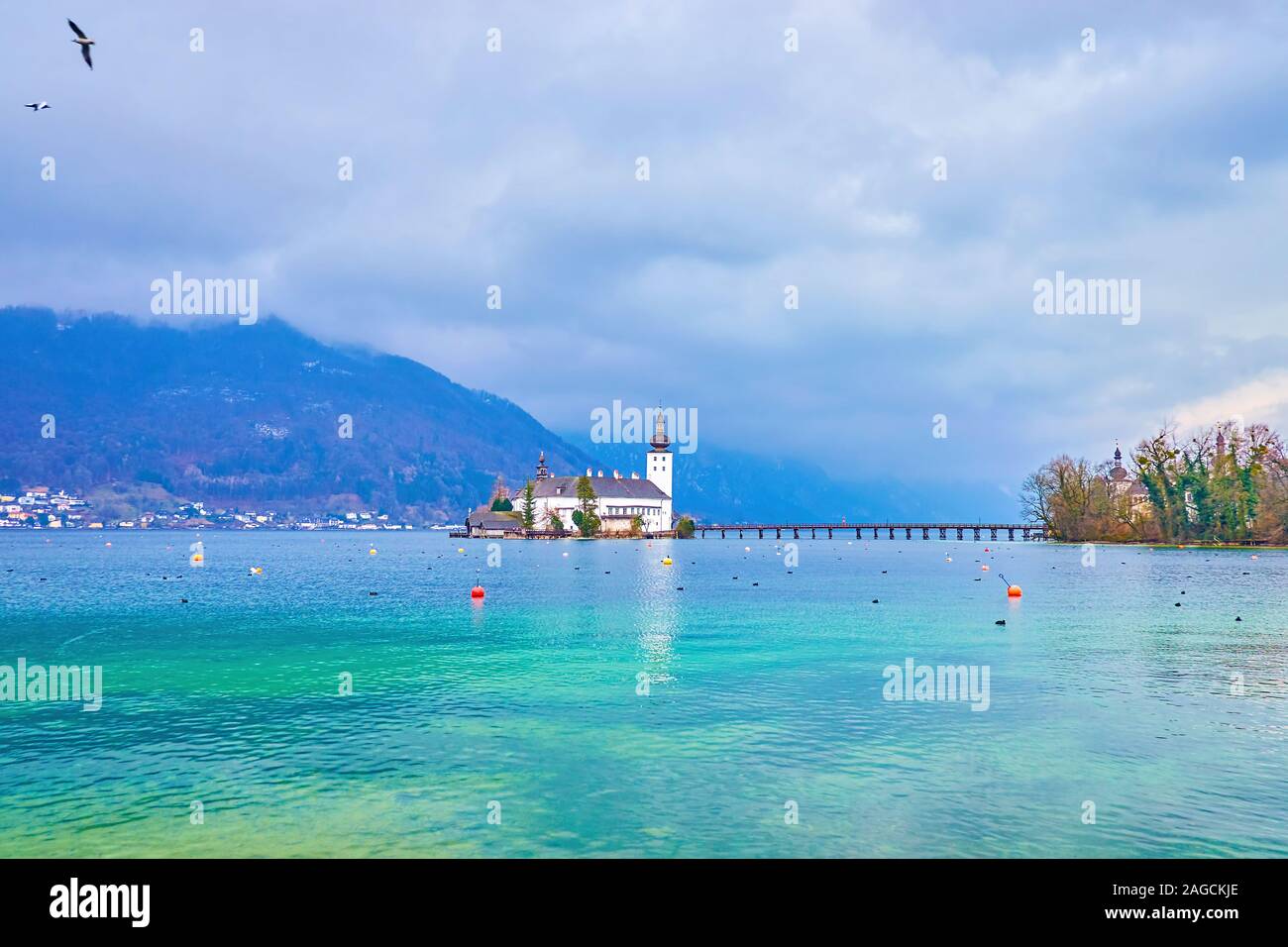 La splendida snow-white Ort Seeschloss lago (castello) in mezzo del Traunsee, che è coperto con pesanti nuvole di pioggia, in bilico nelle Alpi intorno al lago, Gmu Foto Stock