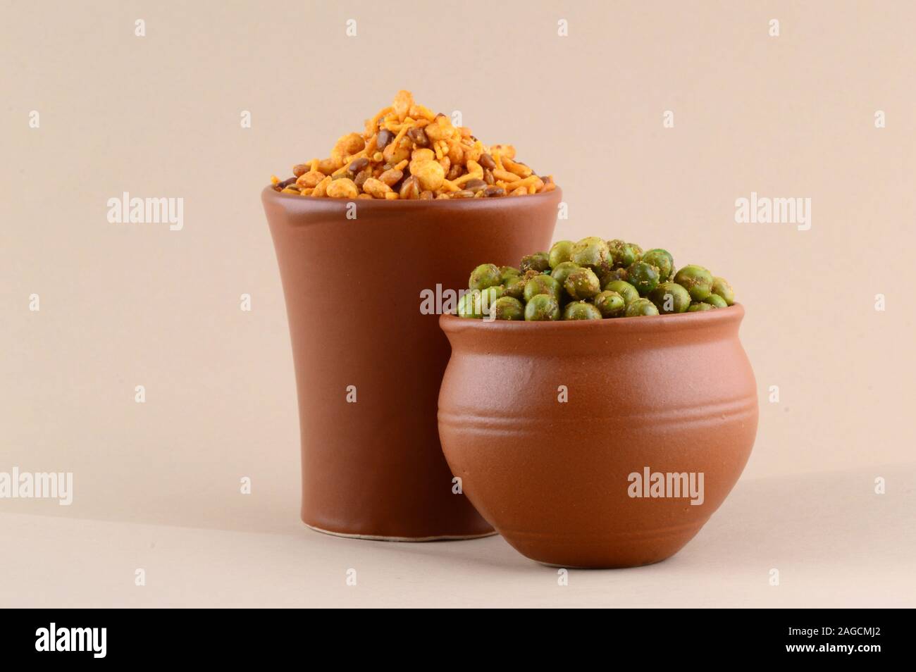 Indian snack: miscela e fritti speziati piselli verdi {chatpata mataró} in pentole di creta. Foto Stock