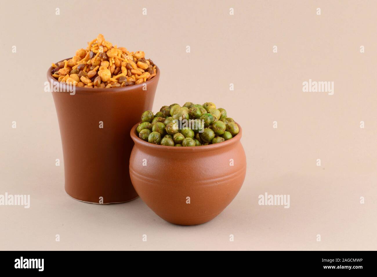 Indian snack: miscela e fritti speziati piselli verdi {chatpata mataró} in pentole di creta. Foto Stock